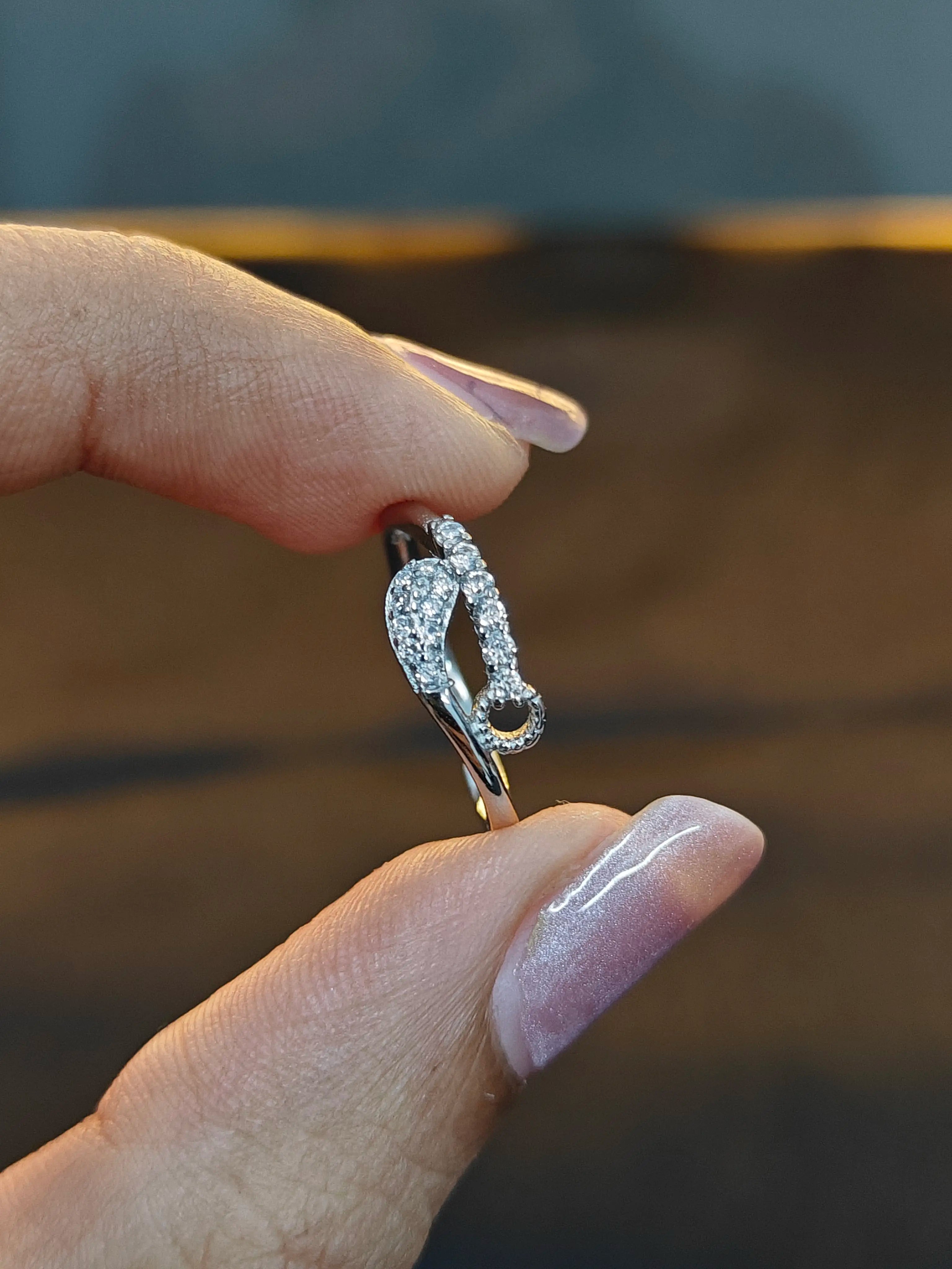 Silver ring with a unique design held by a hand against a blurred background